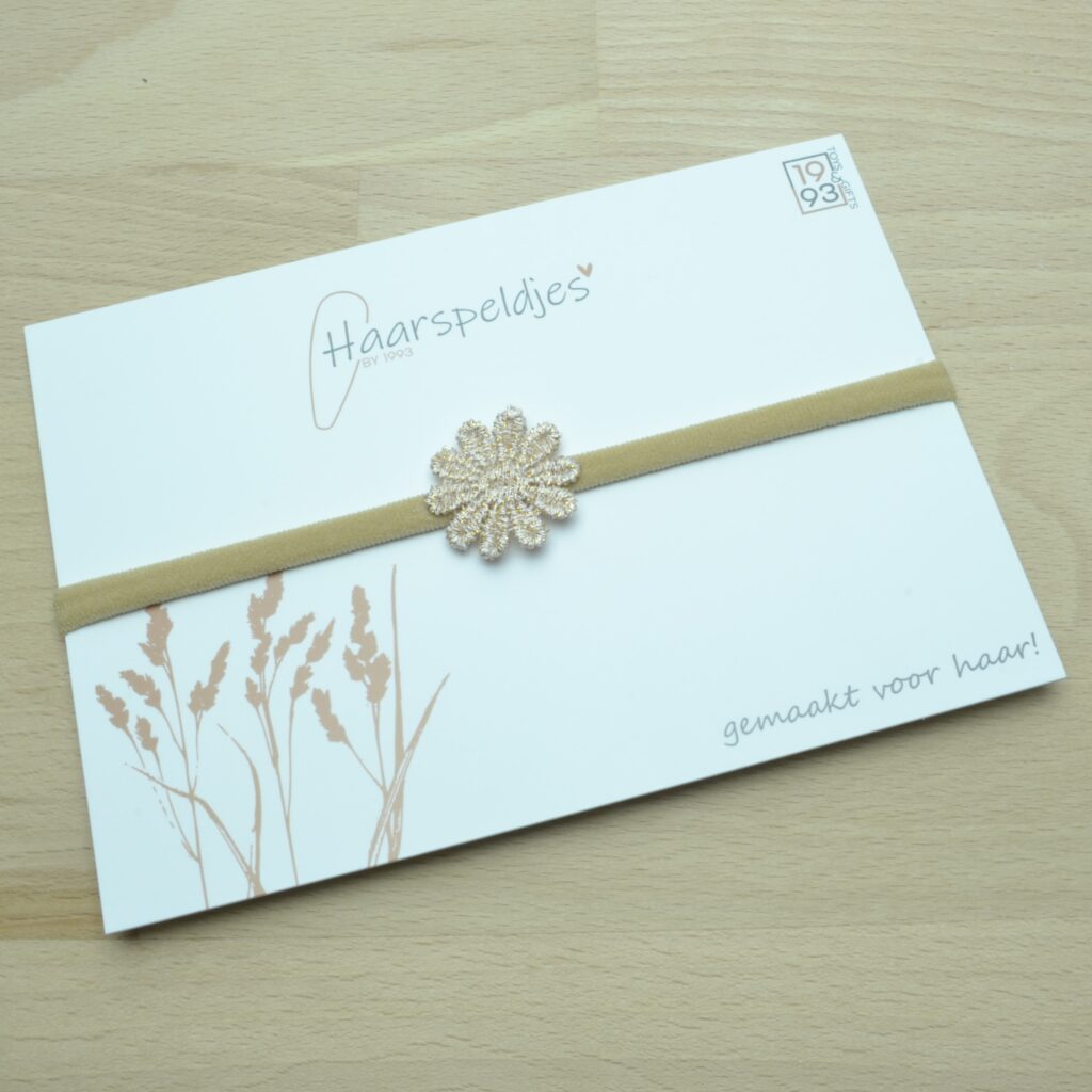 Nylon haarbandje met een bruin gouden bloemetje. gouddraad